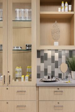 This image of the skincare display shelving at Core Dermatology shows wood display shelves, product bottles, tile backsplash, and warm dermatology office cabinetry.