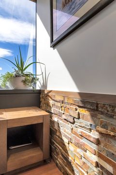 A close-up detail of the Bridge Creek Dentistry waiting room featuring a brick accent wall, built-in side table, plant decor, window light, and warm modern materials.