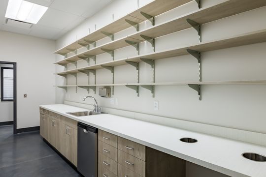This image of the long storage counter at Montclair Animal Clinic shows open shelving, long white countertop, light wood cabinetry, and organized clinic storage.