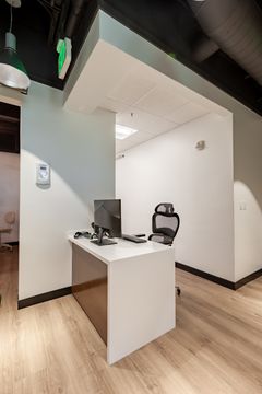 This image of the side reception workstation at Chroma Dental Studio shows a small front desk workstation, arched wall opening, ceiling detail, and clean modern entry finishes.