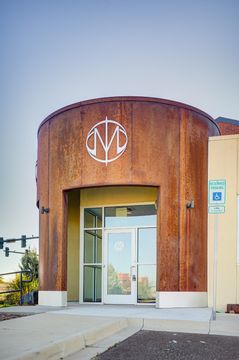 This image of the vertical front door view at Meridian Periodontics of Central Park shows the curved wood entry tower, glass front door, signage, and entry walkway.