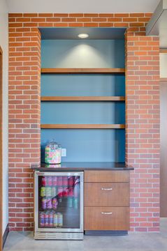 This image of the display shelf detail at Meridian Periodontics of Central Park shows teal shelving, brick wall, decorative accessories, and warm reception area finishes.