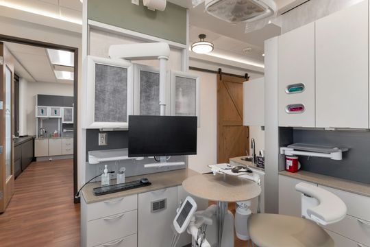 A modern dental operatory at Bridge Creek Dentistry with integrated cabinetry, patient monitor, dental tools, treatment chair, clinical storage, and a clean, efficient workspace.