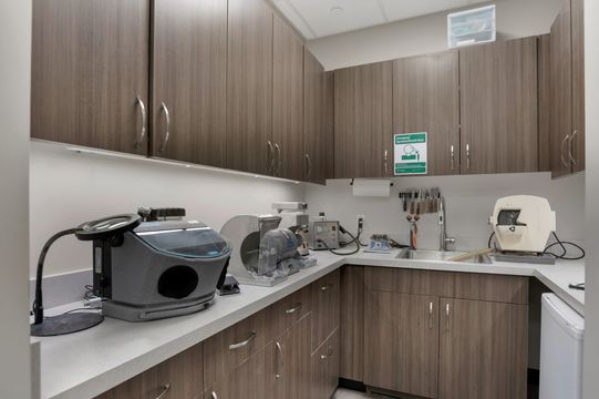 This image of the clinical lab counter at Soult and Swanson Family Dentistry shows brown upper cabinets, countertop equipment, sink station, and organized dental lab supplies.