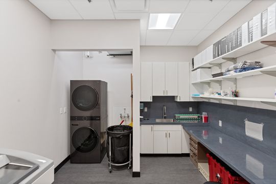 A functional utility and sterilization room at Elevation Dermatology with organized shelving, cabinetry, and laundry equipment.
