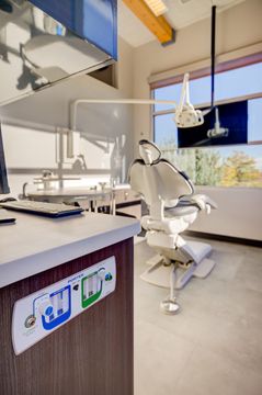 This image of the operatory equipment detail at Meridian Periodontics of Central Park shows dental chair equipment, instrument tray, monitor, window light, and clean clinical flooring.