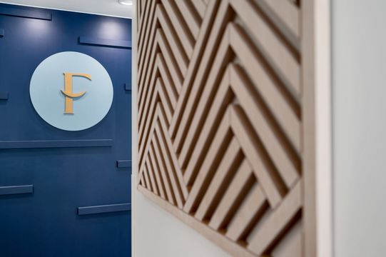 Interior detail of the Foundations Orthodontics logo displayed on a navy accent wall beside a geometric wood feature wall.