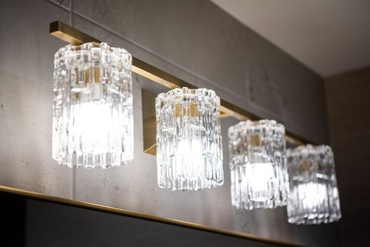This image of the crystal vanity light detail at Collective Health shows crystal wall lights, brass trim, textured wall finish, and upscale interior lighting.