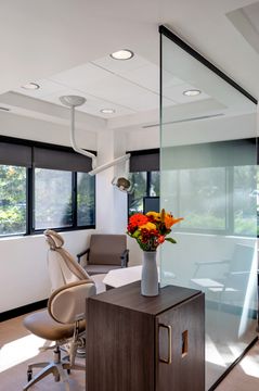 A private orthodontic treatment room at Foundations Orthodontics with natural light, glass partitions, floral decor, and modern equipment.