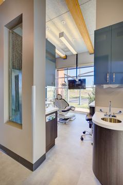 This image of the clinical hallway detail at Meridian Periodontics of Central Park shows operatory entrances, glass panels, curved counters, wood beams, and bright natural light.