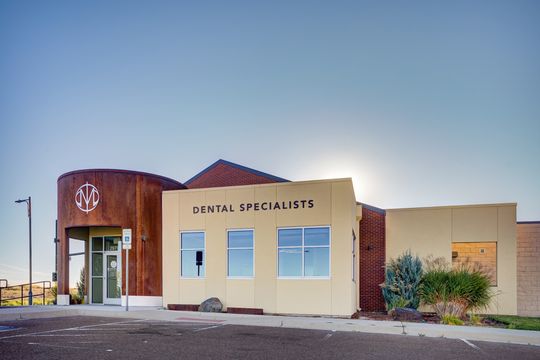 This image of the building signage exterior at Meridian Periodontics of Central Park shows the Dental Specialists facade, entry door, cream exterior walls, and clean landscape beds.