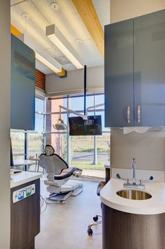 This image of the operatory sink and hallway detail at Meridian Periodontics of Central Park shows curved cabinetry, sink station, treatment room access, wood beams, and window light.