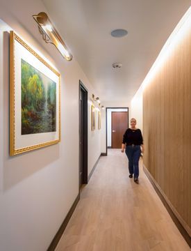This image of the artwork hallway at Collective Health shows framed artwork, warm wall lighting, wood feature wall, and a clean patient corridor.