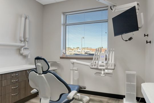 This image of the treatment room with window at Soult and Swanson Family Dentistry shows a dental chair, wall monitor, window view, cabinet storage, and clean operatory layout.