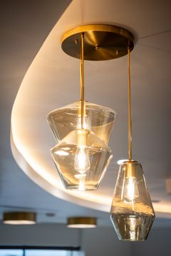 This image of the pendant lighting detail at Collective Health shows glass pendant lights, warm ceiling glow, brass accents, and a refined dental office atmosphere.