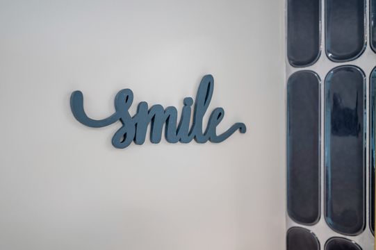 A decorative smile sign and dark vertical tile detail add a friendly branded touch to the Foundations Orthodontics interior.