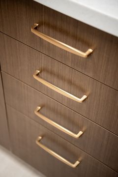 This image of the wood cabinet pull detail at Collective Health shows wood drawer fronts, brass hardware, vertical handles, and warm millwork detail.