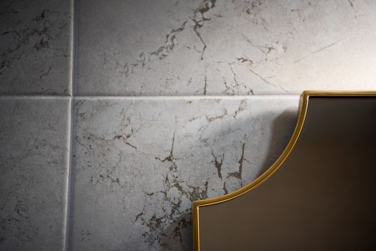 This image of the stone wall and mirror detail at Collective Health shows stone tile, curved mirror edge, brass trim, and elegant dental office finishes.