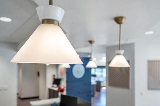 A close-up view of the modern pendant lighting inside Foundations Orthodontics, with the branded logo wall and wood accents softly visible in the background.
