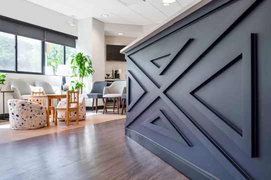 A welcoming Foundations Orthodontics reception and waiting area with a navy geometric accent wall, children’s seating, and modern lounge furniture.