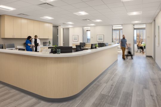This image of the clinical reception counter with staff at Core Dermatology shows staff at a long front counter, bright flooring, exam room access, and medical office workstations.