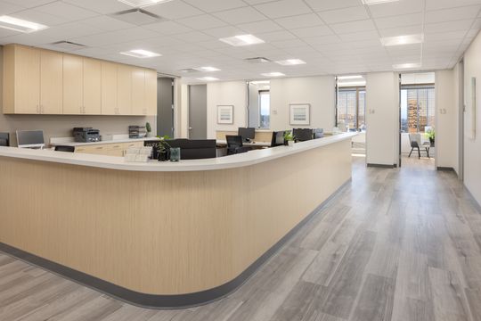 This image of the clinical workstation counter at Core Dermatology shows a long wood reception-style counter, workstations, hallway access, and bright medical office lighting.