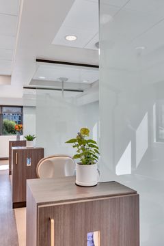 A modern counter area at Foundations Orthodontics featuring pendant lighting, dark tile, leather chairs, and a floral arrangement.