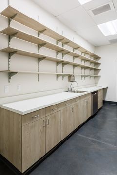 This image of the tall storage shelving at Montclair Animal Clinic shows long wall shelving, white counters, wood lower cabinets, and bright storage room lighting.