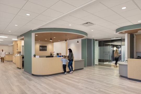 This image of the dermatology exam with clinician at Core Dermatology shows a clinician, seated patient, exam chair, large windows, and bright clinical workspace.