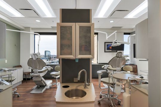 An open treatment bay at Bridge Creek Dentistry featuring multiple dental chairs, integrated cabinetry, clinical sinks, overhead equipment, and bright contemporary finishes.