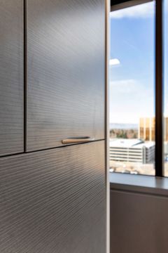 A vertical interior detail at Bridge Creek Dentistry showing dark textured cabinetry, window light, wood flooring, and a clean contemporary dental office finish.