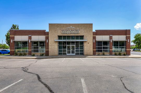 Exterior view of the Elevation Dermatology building with brick and stone facade, storefront windows, and patient parking.