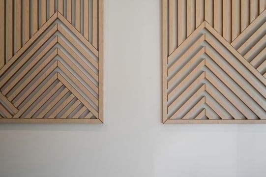 Custom wood wall panels with chevron-inspired geometric patterns add warmth and texture to the Foundations Orthodontics office design.